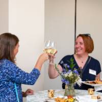 Two woman standing at taller events table cheersing